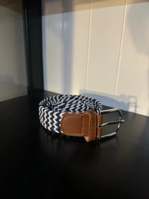 Flätat bälte blå vitt - Ett riktigt snyggt flätat bälte. Bältet är blå vitt och passar till det mesta. Skicket är otroligt bra då de endast är använt någon enstaka gång. Skriv vid frågor och kolla gärna in min profil för fler bälten och kläder!