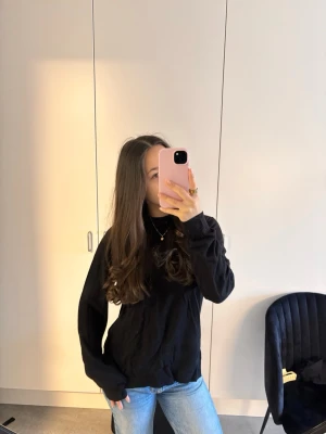 Svart långärmad stickad tröja - Säljer en svart långärmad stickad tröja i klassisk modell. Tröjan har en rak passform och är tillverkad i ett mjukt material. Enkel och stilren design utan synliga detaljer eller mönster.