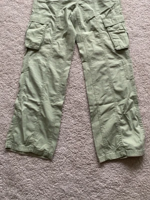 Ljusgröna cargobyxor med fickor - Säljer ett par ljusgröna, mintgröna cargobyxor med bred passform och stora sidofickor. Byxorna har elastisk midja med snörning och är tillverkade i ett mjukt bomullsmaterial. Perfekta för dig som gillar en avslappnad och trendig stil.