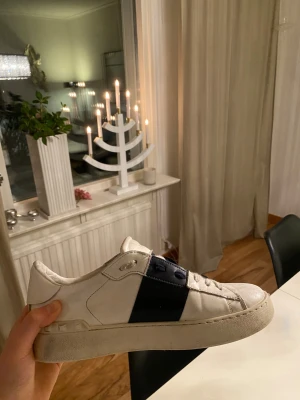 Valentino Open Garavani sneakers  - Säljer mina Valentino Open Garavani sneakers. Vit modell med mörkblå detalj i mitten. 