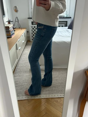 Blå bootcut jeans med låg midja - Säljer ett par klassiska blå bootcut jeans med låg midja och lätt slitning. Jeansen har fem fickor och stängs med knapp och dragkedja. Perfekta för dig som gillar en avslappnad men ändå trendig look. Diesel, ca 38❤️