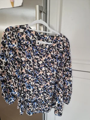 Mönstrad blus från Part Two med knappar - Blus med abstrakt mönster i blått, svart, beige och vitt från Part Two. Modellen har rund halsringning, knappar framtill.. Tillverkad i ett lätt och luftigt tyg som ger en avslappnad men trendig look.