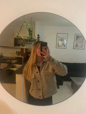 Beige overshirt från Dobber - Säljer en beige overshirt från Dobber med klassisk krage och stora bröstfickor med knappar. Jackan har raka ärmar och en boxig passform, perfekt att slänga över en t-shirt. Materialet är mjukt och känns som ullblandning.