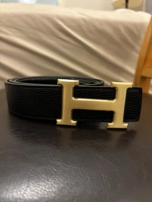 H bälte - svart/guld - Klassiskt H bälte med en unik guld buckla, 105cm. Pris kan diskuteras vid snabb affär.