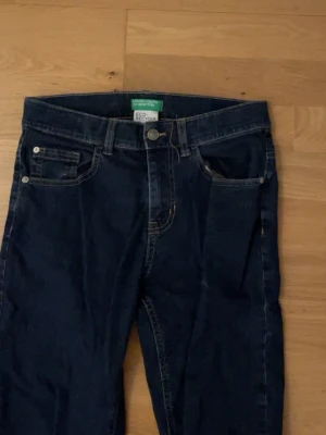 Mörkblå raka jeans Eco Recycle - Snygga mörkblå jeans från Eco Recycle med klassisk femficksmodell och raka ben. Jeansen har normalhög midja och är tillverkade i ett slitstarkt denimtyg. Perfekta för dig som gillar en enkel och tidlös stil.