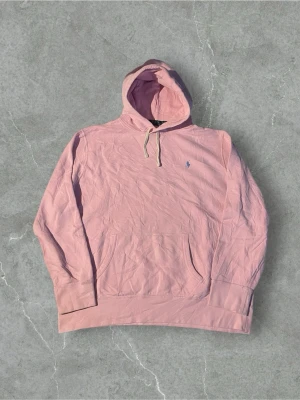 Rosa hoodie från Polo Ralph Lauren | XXL - Säljer en ljusrosa hoodie från Polo Ralph Lauren med klassisk huva och dragsnören. Tröjan har en liten broderad logotyp på bröstet och en stor magficka framtill. Mått finns i bilder, behöver en strykning! 