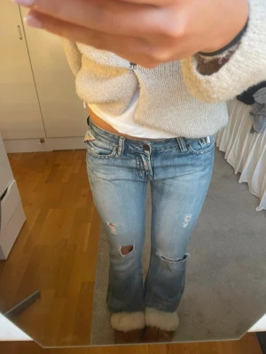 Blå lowrise jeans från Replay!🤍 - Säljer ett par ljusblå low rise jeans från Replay med slitningar och hål på benen. Jeansen har broderade detaljer på bakfickorna och låg midja. Klassisk femficksmodell i denim med cool vintagekänsla.