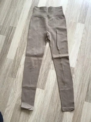 Beiga ribbade träningstights/leggings från New Apparel, stl XS - Säljer ett par beiga ribbade träningstights/leggings från New Apparel. Storlek XS. Bara använda ett par gånger, så näst intill nyskick. Just nu fri frakt, så du betalar bara för tightsen. Jag har fler plagg ute, och hittar du något mer från min garderobsutrensning, så skickar jag allt i samma paket.