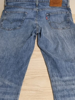 Levi's 511 blå jeans W33 L34 - Säljer ett par klassiska blå Levi's 511 jeans i rak modell. Jeansen har fem fickor, snygga kontrastsömmar och den ikoniska röda Levi's-lappen på bakfickan. Tillverkade i slitstark denim med läderpatch bak i midjan.