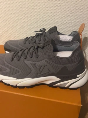 Louis Vuitton sneakers - Säljer mina skor, använda 1 gång! Snygga grå sneakers från Louis Vuitton med LV-logga på sidan. Storlek 44 och passar till allt! Kartong och påse medföljer.