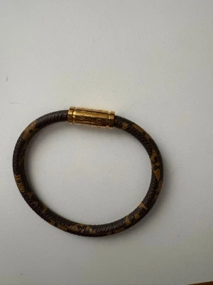 Brunt armband med guldfärgat spänne - Snyggt armband i brunt med djurmönster och ett stilrent guldfärgat magnetlås. Armbandet har en rund form och är gjort i konstläder med metallspänne. Perfekt accessoar för att lyfta din outfit. 19mm