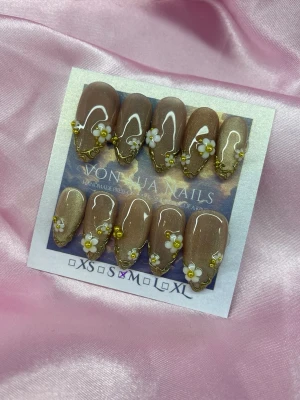 Gilda (M);Medium Almond - Snygga handgjorda press-on naglar i brun cateye metallic med medium mandelform. Dekorerade med vita 3D-blommor, 3D nailart i guld och skimrande cateye finish. Perfekt för dig som vill ha en unik och trendig nagelstil. Handgjorda och lätta att applicera.M: 16 mm, 12 mm, 12,5 mm, 11,5 mm, 10 mm