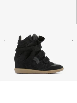 Svarta Isabel Marant sneakers - Snygga svarta sneakers från Isabel Marant med kilklack och kardborreband. Skorna är gjorda i mocka och har en beige sula. Perfekta för dig som vill ha både stil och höjd i ett par sneakers. Köpta här på plick så därför saknas tyvärr äkthetsbevis. Storlek 37