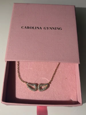 Guldhalsband från Carolina Gynning - Snyggt halsband i guldton från Carolina Gynning med ett unikt ögonformat hänge dekorerat med gnistrande stenar. Kedjan är tunn och elegant, och hänget har en modern design som verkligen sticker ut. Kostar 2600 i nypris! 