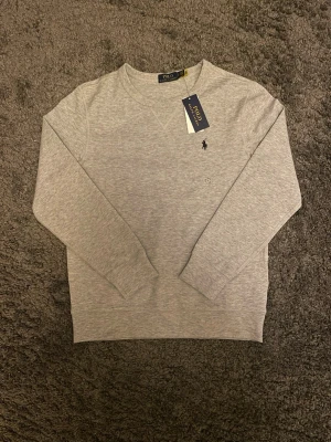 Ralph Lauren Tröja - En grå långärmad tröja från Ralph Lauren. Helt ny med prislapp kvar✅. Skicka gärna rimliga prisförslag och skriv om du har frågor!😄