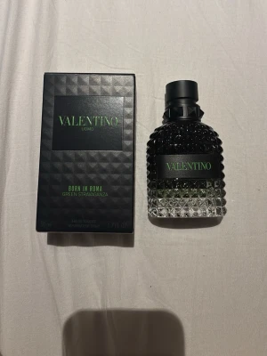 Valentino Uomo Born In Roma parfym - Valentino Uomo Born In Roma Green Stravaganza är en exklusiv herrparfym i en elegant svart och grön glasflaska med nitar och mönstrad botten. Flaskan rymmer 50 ml och kommer i en matchande svart kartong med gröna detaljer. Doften är modern och lyxig.