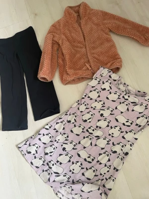Svarta tights +Fleecejacks +Ljuslila nattlinne med panda-mönster - Svarta tights +Fleecejacka fluffigt och skön  Supersött ljuslila nattlinne med gulligt panda-mönster över hela plagget. Nattlinnet har korta ärmar och är gjort i mjukt, bekvämt material som passar perfekt för mysiga kvällar hemma.