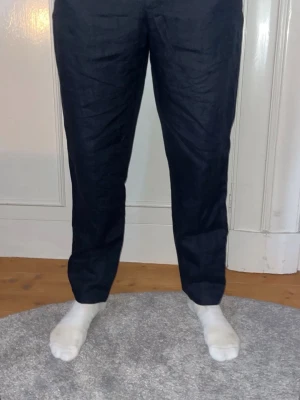 Mörkblå linnebyxor från Zara  - Snygga mörkblå linnebyxor i rak passform. Byxorna har klassisk design och passar perfekt till en dressad look. Tillverkade i ett slätt tyg som ger en stilren känsla. Perfekta för dig som vill ha en clean och tidlös stil.