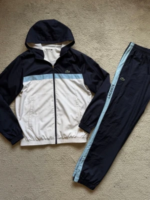Lacoste Tracksuit  - Fräsch Lacoste Tracksuit. Använd några gånger. Inget som är sönder. Justerbara byxor längst ner. Äkthetsbevis finns. För mer frågor eller bilder är det bara att skriva! 