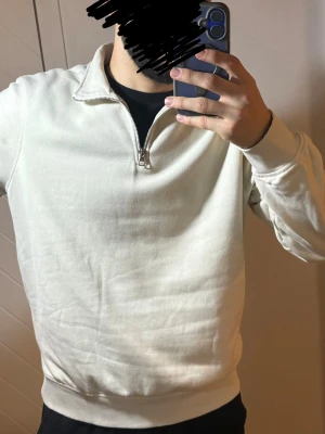Beige half zip tröja C&A - Säljer en stilren beige sweatshirt med halv dragkedja och ståkrage. Tröjan har långa ärmar, ribbade muddar och är tillverkad i mjukt bomullsmaterial. Perfekt för en avslappnad och trendig look.