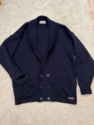 Marinblå/mörkblå Cardigan Kofta Perini - 🛥️ Säljer en riktigt snygg mörkblå Cardigan kofta från Perini, med coola detaljer.   Storlek: XL (men passar som en M/L) Skick: Riktigt bra skick, som ny och har inga skador!  Material: 100% ull  Made in Sweden🇸🇪