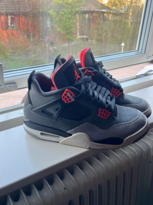 Air Jordan 4 Retro Dark Grey/Infrared - Air Jordan 4 Retro sneakers i färgerna mörkgrå, svart och infrared 23. Klassisk siluett med coola detaljer och ikonisk Jumpman-logga. Perfekta för dig som vill sticka ut med en tidlös och sportig look. Tillverkade i slitstarka material och med skön passform.