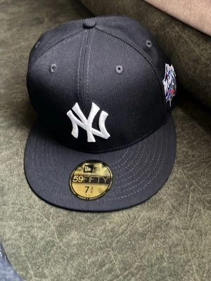 New Era Yankees svart keps 59FIFTY 7 3/4  - Säljer en helt ny svart New Era 59FIFTY keps med New York Yankees-logga i vitt framtill och patch på sidan. Klassisk rak skärm och broderade ventilationshål. MLB-logga baktill. Perfekt för dig som gillar streetwear och sportig stil. Den var för stor därför jag säljer den helt ny 