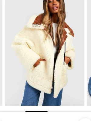 Dubbelsidig oversized teddyjacka - Säljer en oversized teddyjacka i krämvitt med bruna detaljer och fusk-läder på krage och rygg. Går även att vända ut och in och ha lädret utåt. Jackan har stora fickor, bred krage och coola spännen vid halsen. Perfekt för dig som vill ha en trendig och mysig look i höst och vinter.