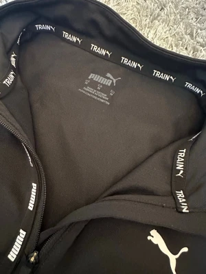 Svart zip-up tröja från Puma - Snygg svart träningsjacka från Puma med halv dragkedja framtill och diskret Puma-logga på bröstet. Använd fåtal gånger men ser som ny ut!❤️(Skriv om du har frågor)