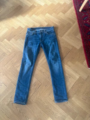Helt nya Slim Nudie Jeans lean dean 28W L32 - Säljer ett par Helt nya klassiska blå slim fit jeans från nudie. Modellen är Lean dean som är deras Snyggaste slim fit modell enligt mig. Jeansen har en snygg tvätt och raka ben. Perfekta till en avslappnad stil och lätta att matcha.