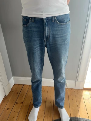 Blå raka jeans i klassisk modell - Snygga blå jeans med rak passform och klassisk femficksdesign. Jeansen har en medelhög midja och subtila slitningar framtill för en avslappnad look. Tillverkade i denim med lätt stretch för extra komfort. Stl 29-34. Sitter mer som 30-32/33. Kan gå ner i pris vid snabb affär 