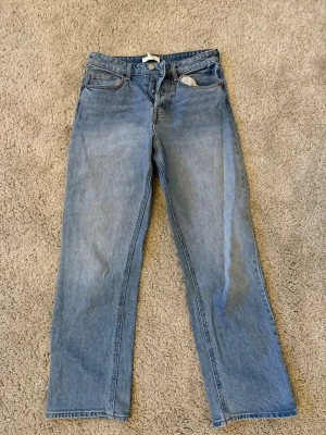 Blå raka jeans med klassisk passform och medelhög midja - Ett par ljusblå jeans med raka ben och figurnära passform. Jeansen har normal midja och är tillverkade i denim. 