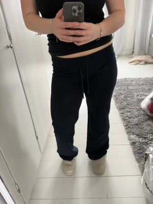Svarta mjukisbyxor med dragsko - Säljer ett par svarta mjukisbyxor med bred resår i midjan och dragsko för skön passform. Byxorna har raka ben och är tillverkade i mjukt, stretchigt material som passar perfekt för chill dagar. Enkla att matcha med hoodie eller t-shirt.
