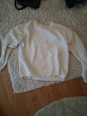 Vit stickad tröja  - Mysig vit stickad tröja med rund hals och långa ärmar. Tröjan har en enkel och clean design med ribbade muddar vid ärmslut och nederkant. Perfekt för lager på lager och passar till det mesta i garderoben.