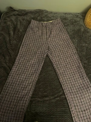 Berhska Lila rutiga kostymbyxor Bershka - Säljer ett par lila kostymbyxor från Bershka i storlek 36. Byxorna har ett rutigt mönster i svart och vitt, raka ben och hög midja. Materialet är strukturerat och ger en trendig look. Perfekta för dig som vill sticka ut med färg och mönster.