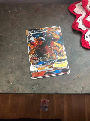 Charizard GX Pokémonkort - Säljer ett Charizard GX samlarkort från Pokémon TCG med färgstark och glansig design. Kortet har attacker som Wing Attack, Crimson Storm och Raging Out GX. Perfekt för dig som gillar att samla eller spela Pokémonkort. Kortet är fejk så det får billigt pris