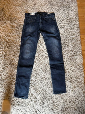Mörkblå skinny jeans från Replay - Säljer ett par mörkblå skinny jeans från Replay med klassisk femficksdesign och snygga slitningar framtill. Jeansen har en smal passform och kontrastsömmar som ger en modern look. Perfekta för dig som gillar stilrena och tidlösa jeans.