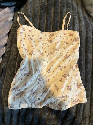 Blommig linnetopp med knappar - Söt linnetopp med smala axelband och blommigt mönster 