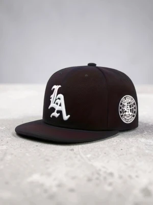 Svart LA snapback keps - Snygg svart snapback keps med stor vit LA-logga framtill och en rund Los Angeles California-patch på sidan. Platt skärm och klassisk streetwear-look. Perfekt för dig som vill ha en stilren och trendig accessoar till din outfit.