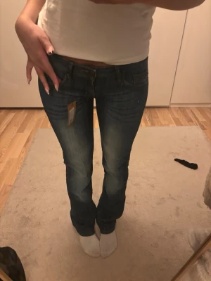 Low waist jeans  - Säljer ett par snygga blå lågmidjade jeans med klassisk femficksmodell och lätt slitna detaljer framtill. 