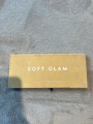 Soft Glam ögonskuggspalett Anastasia - Soft Glam ögonskuggspalett från Anastasia Beverly Hills med 14 nyanser i både matta och skimrande toner. Färgerna går i neutrala, varma och guldiga nyanser som Dusty Rose, Burnt Orange, Bronze och Mulberry. Paletten har en rektangulär form och ett elegant beige sammetsetui. De. Är inte använd men den har blivigt lite blandad som på bilden 