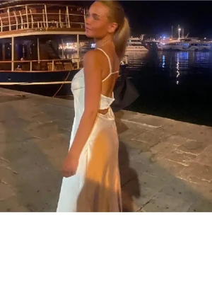 Vit långklänning från Zara i satin - vit långklänning från Zara i glansigt satinmaterial. Klänningen är axelbandslös med en smickrande, figurnära passform och lätt utsvängd nederdel. Perfekt för sommarens speciella tillfällen. Har lite slitage som knappt syns, kom privat för fler bilder.💕