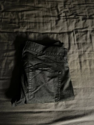 Svarta raka jeans i denim - Säljer ett par svarta jeans med raka ben och klassisk femficksdesign. Jeansen är tillverkade i mjukt denimtyg och har en enkel, stilren look utan synliga loggor. Perfekta för dig som gillar minimalistisk stil. I storlek w 33 och l 32