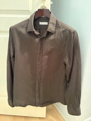 Mörkgrön skjorta från Zara i linne/bomull blandning - Stilren mörkgrön skjorta från Zara med klassisk krage och knappar framtill. Tillverkad i mjuk bomull som känns skön mot huden. Perfekt för dig som gillar en enkel men snygg look. Långärmad modell som passar till många olika outfits.