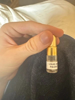 Louis Vuitton Pacific Chill parfymprov - Litet parfymprov från Louis Vuitton med doften Pacific Chill. Flaskan är genomskinlig med guldfärgat lock och etikett med doftnamnet. Perfekt att ha med i väskan eller testa innan du köper en större flaska. 1ml