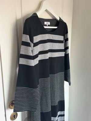 Svart och grå randig klänning Soyaconcept - Snygg svart och grå långklänning från Soyaconcept med breda och smala ränder. Klänningen har lång ärm och en avslappnad passform. 