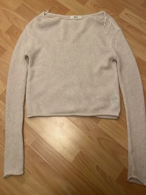 Ljusbeige stickad tröja Gina Tricot - Ljusbeige stickad tröja från Gina Tricot i mjuk ullblandning. Tröjan har rund halsringning, långa ärmar och en enkel, rak passform. Perfekt att matcha med jeans eller kjol för en clean look. Använd en gång 