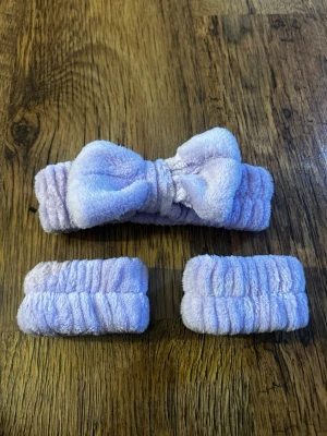 Ljuslila fluffigt hårband med rosett - Säljer ett set med ett mjukt, fluffigt hårband i ljuslila med stor rosett framtill samt två matchande scrunchies. Perfekt för att hålla håret borta vid sminkning eller hudvård. Materialet är plyschliknande och känns riktigt gosigt. Använd 2 gånger, tvättade.