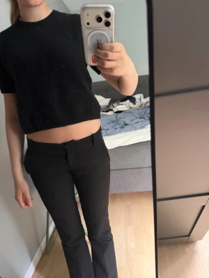 Svart croppad topp med kort ärm - En enkel och stilren svart croppad topp med korta ärmar och rund hals. Toppen har en loose passform och är perfekt för dig som gillar en avslappnad men trendig look. Materialet känns mjukt och bekvämt mot huden.