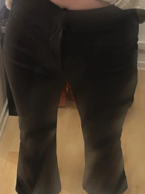 Svarta kostymbyxor från Zara - Stilrena svarta kostymbyxor från Zara med utsvängda ben och diskreta fickor framtill. Byxorna har en klassisk midja och är perfekta för en clean och snygg look. Materialet känns mjukt och har en lätt stretch för extra komfort.